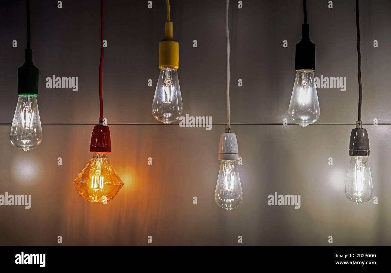 Light bulbs with multi-colored electric cords on a dark background. Stock Photo
