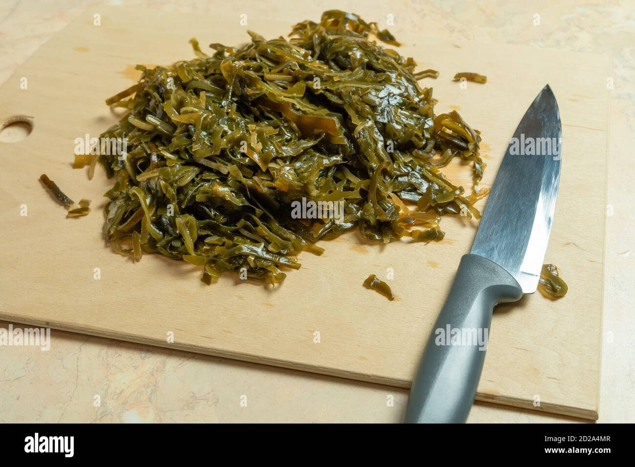 Marinated seaweed laminaria, knife, wooden Board on the table close-up Stock Photo