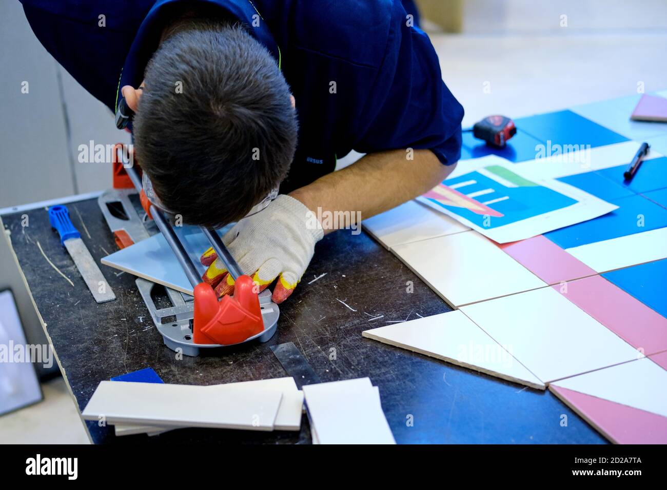 A man cuts ceramic material with a tile cutter, close-up Stock Photo