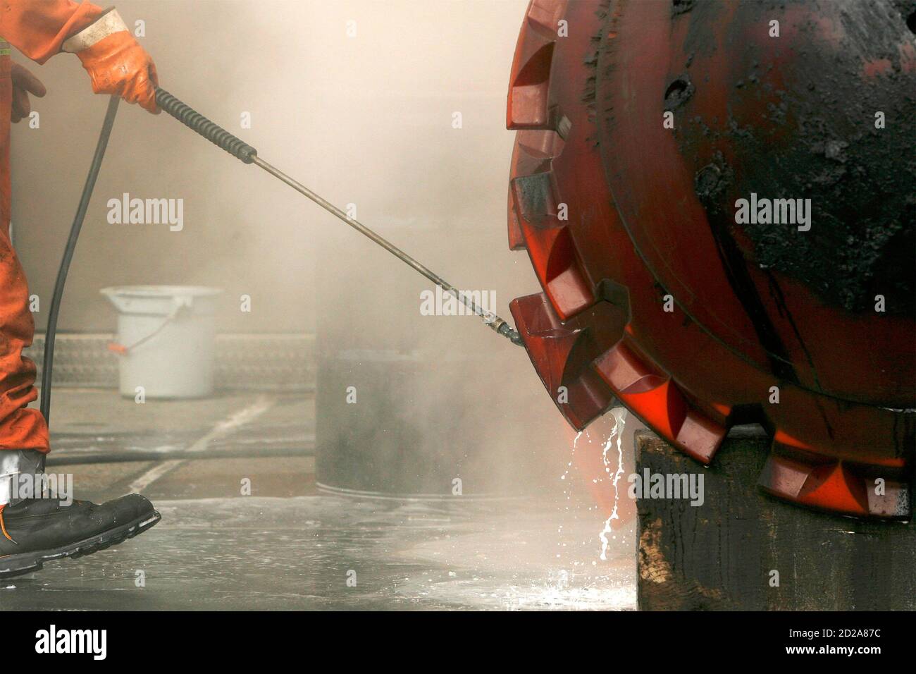 A worker uses a pressure hose to clean a paraffin cleaning 'pig' at the Trans-Alaska Pipeline Marine Terminal in Valdez, Alaska on August, 8 2008. Paraffin 'pigs' are inserted to scrape the walls of the 48-inch diameter pipeline to clean the waxy buildup that occurs when oil cools as it flows from the oil fields in Prudhoe Bay.  REUTERS/Lucas Jackson  (UNITED STATES) Stock Photo