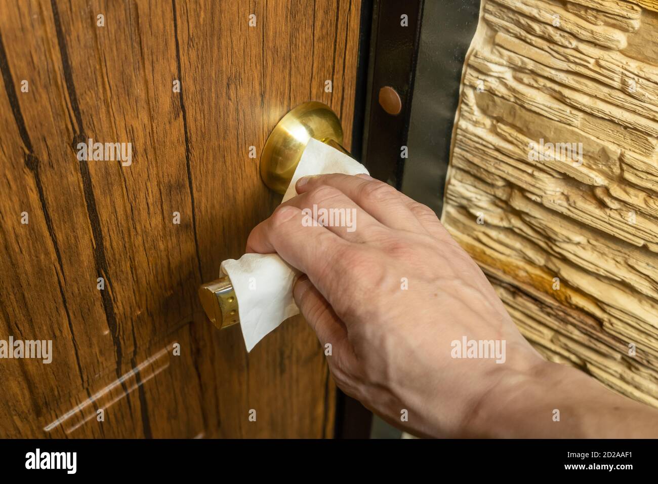 Man's hand grabs the front door handle with a white napkin. A necessary method for preventing