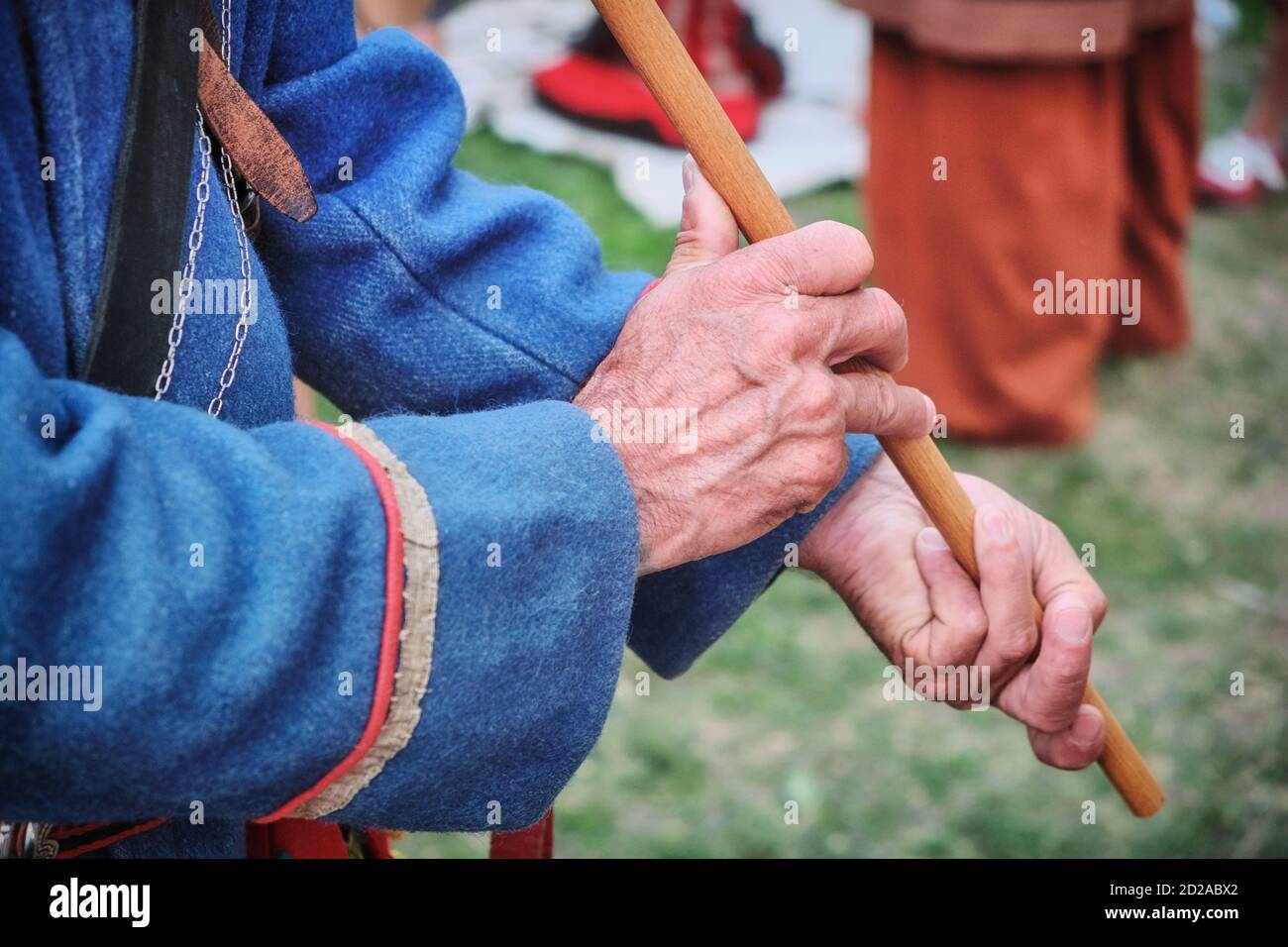 The flutist plays a national musical instrument. An old man dressed in retro style with a pipe in wrinkled hands. Flute in an elderly man in tradition Stock Photo