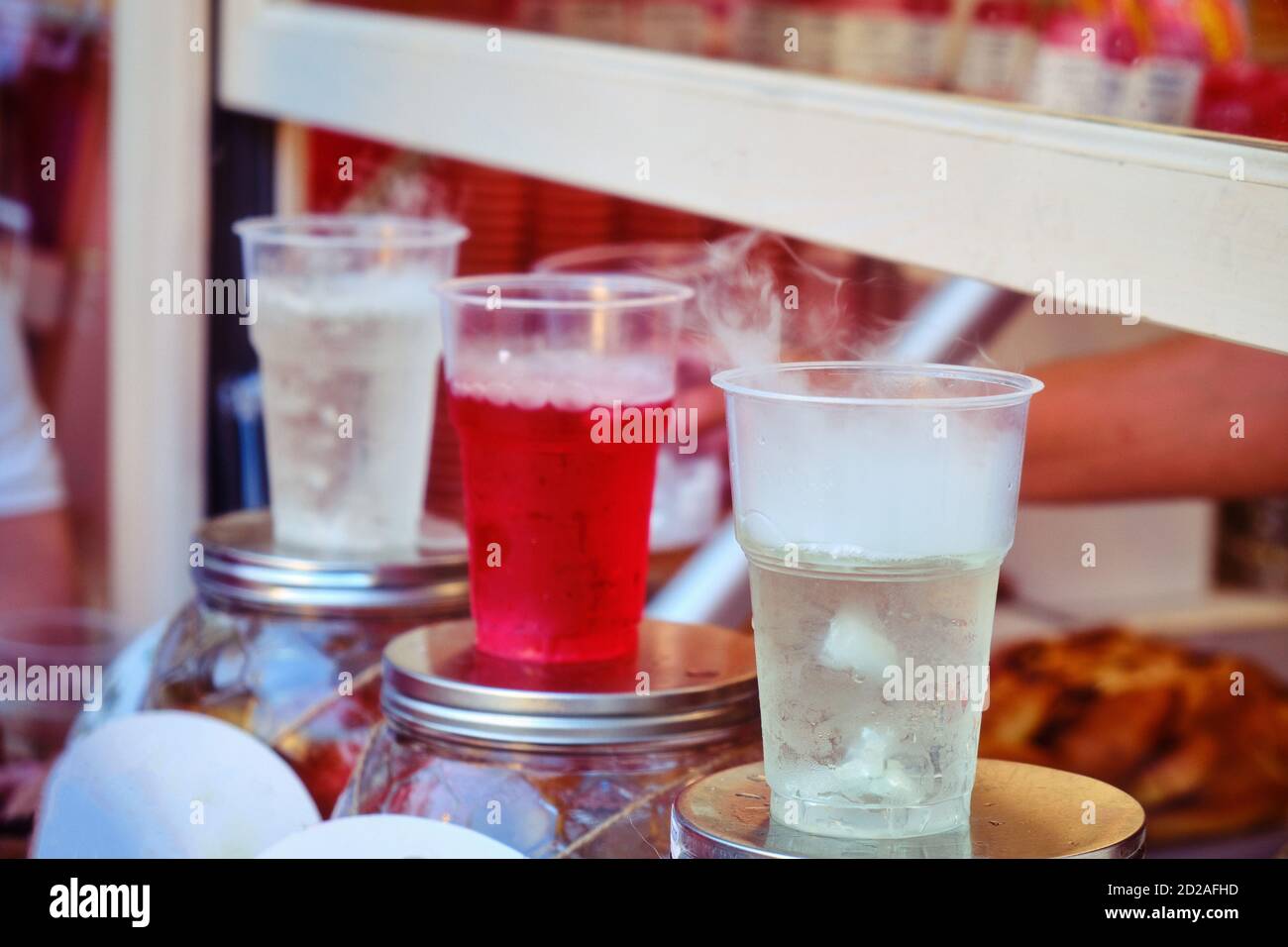 Sale of cold drinks in a street shop. Soda in plastic cups on the ...
