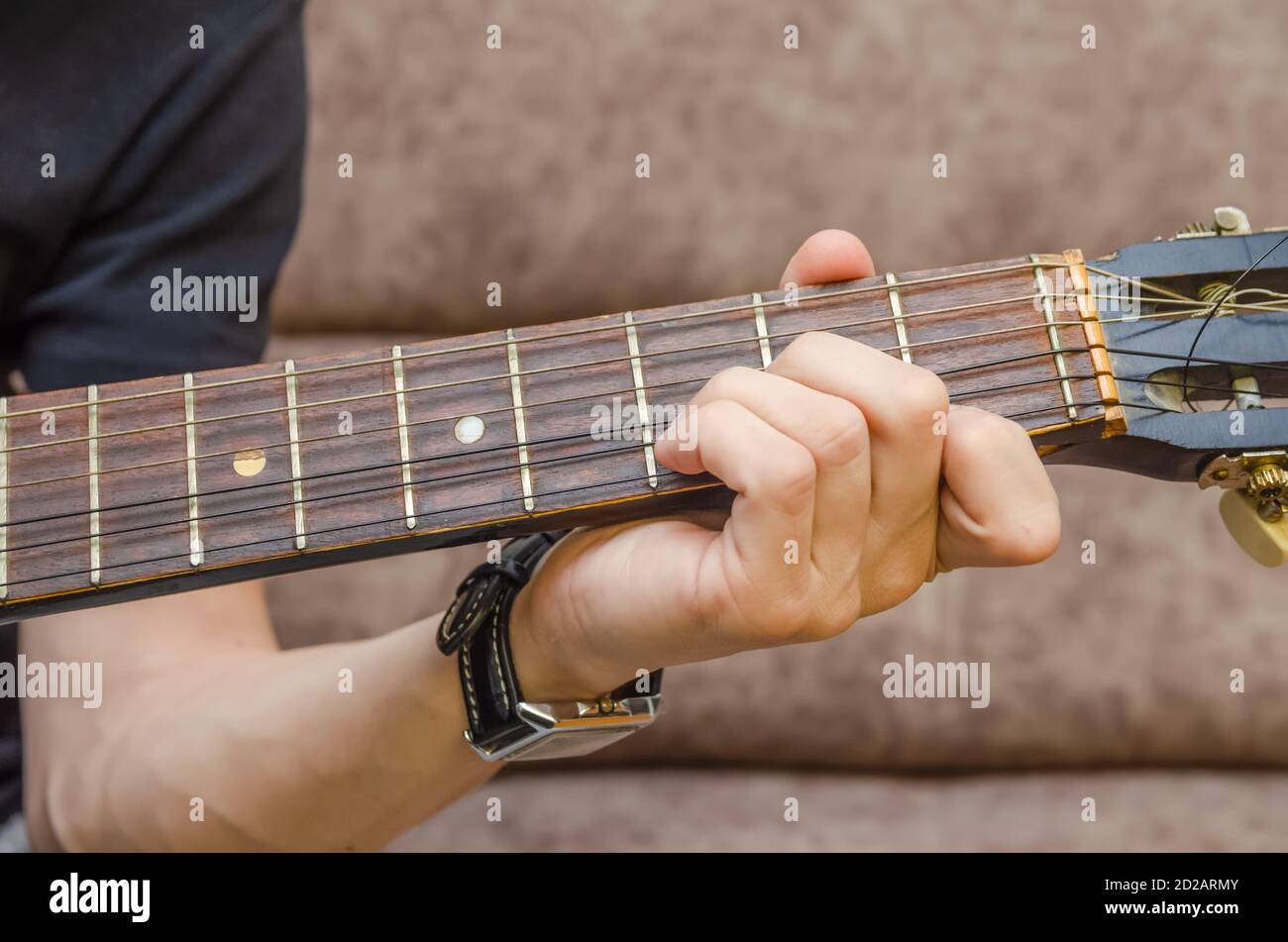 Close-up of a guitarist's hand on an acoustic guitar. Guitar player's hand on the fretboard of an acoustic guitar close-up Stock Photo