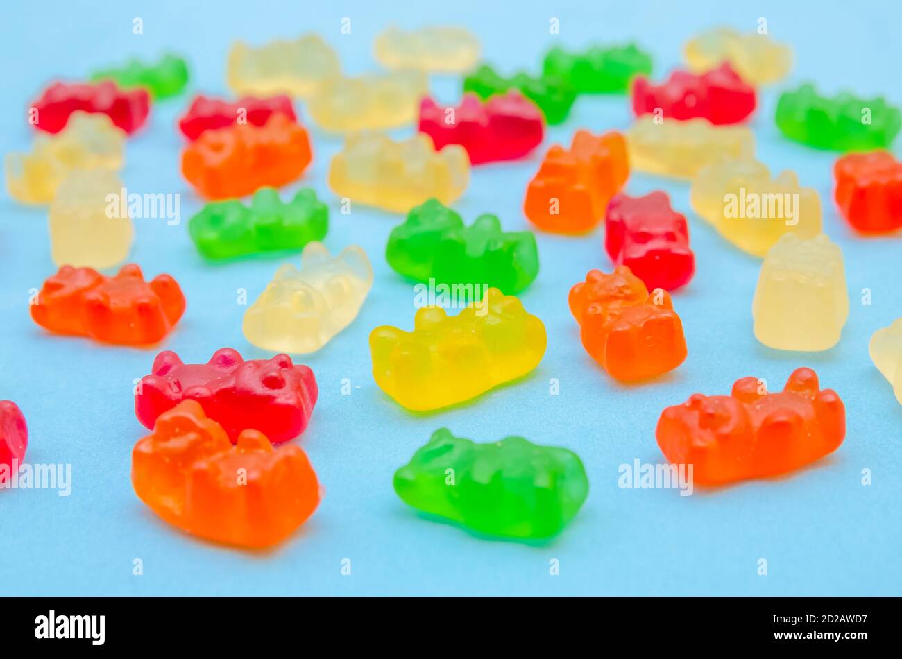 Delicious bright colored jelly bears on a blue background laid out in the same order, side view Stock Photo