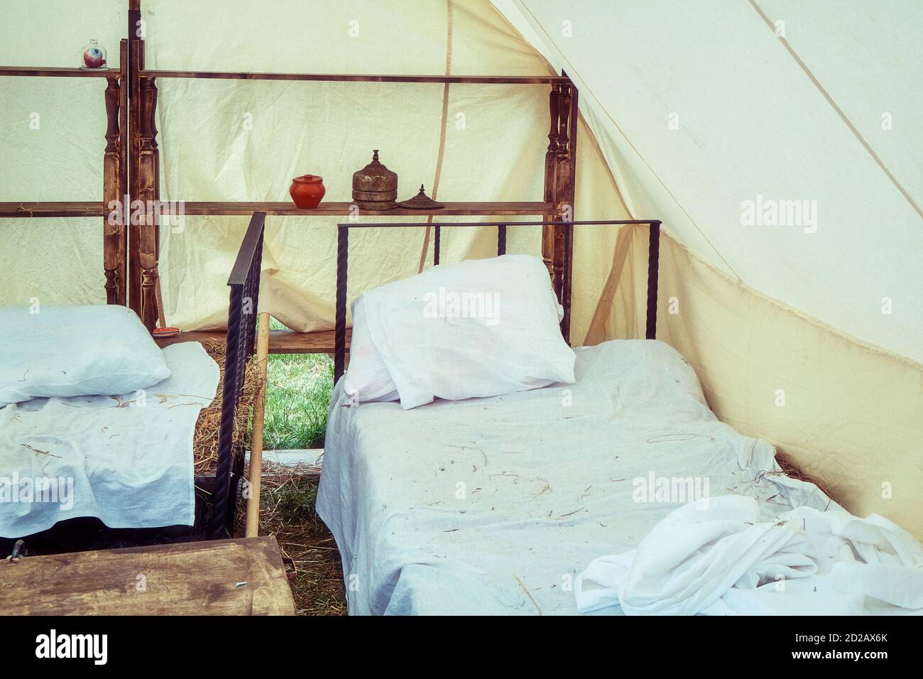 Bed under a large tent retro field hospital. Military field medicine in the 18th or 19th century. Portable hospital for wounded soldiers. Stock Photo