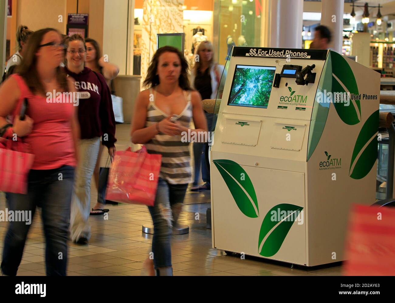 Shoppers walk past an ECO ATM machine at a shopping mall in Rancho Bernado, California April 20, 2010. A small start-up company from San Diego is building ATM type kiosks that can scan and price old used cellphones and then pay the customer on the spot for the device. Picture taken April 20, 2010.   REUTERS/Mike Blake  (UNITED STATES - Tags: ENVIRONMENT SOCIETY SCI TECH BUSINESS) Stock Photo