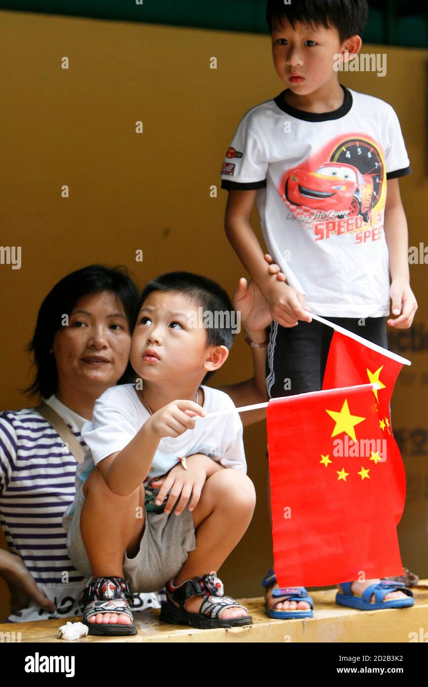 Bystanders hold Chinese flags as they watch a parade celebrating the