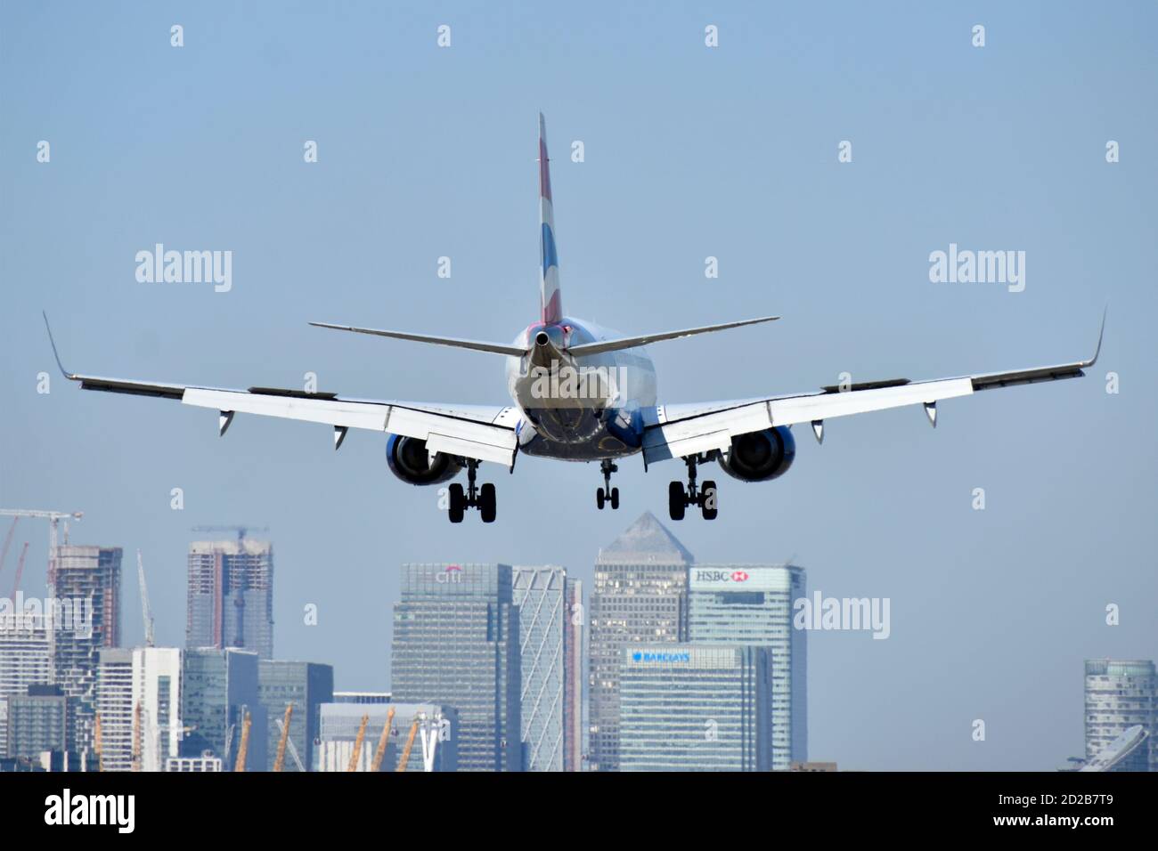 British Airways  airplane landing East London City Airport with Canary Wharf modern urban skyline in London Docklands beyond Newham England UK Stock Photo