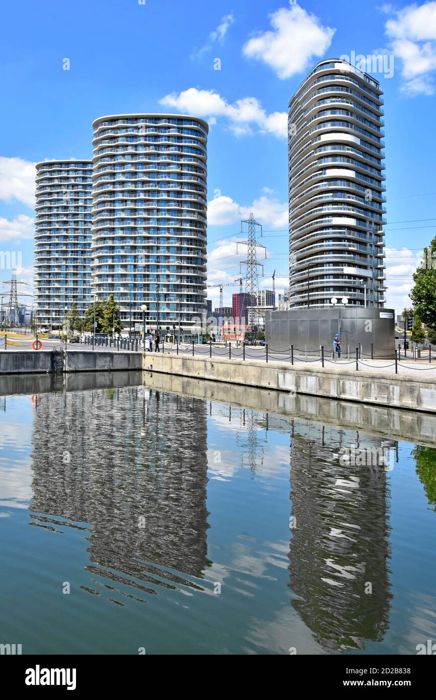 Reflections in the Royal Docks water of modern high rise housing apartment block structures of homes in flats with balconies Newham East London UK Stock Photo