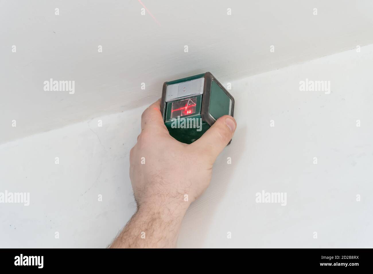 Marking the wall with a laser level for installation of a stretch ceiling.  Red light on the wall. Repair and construction Stock Photo - Alamy