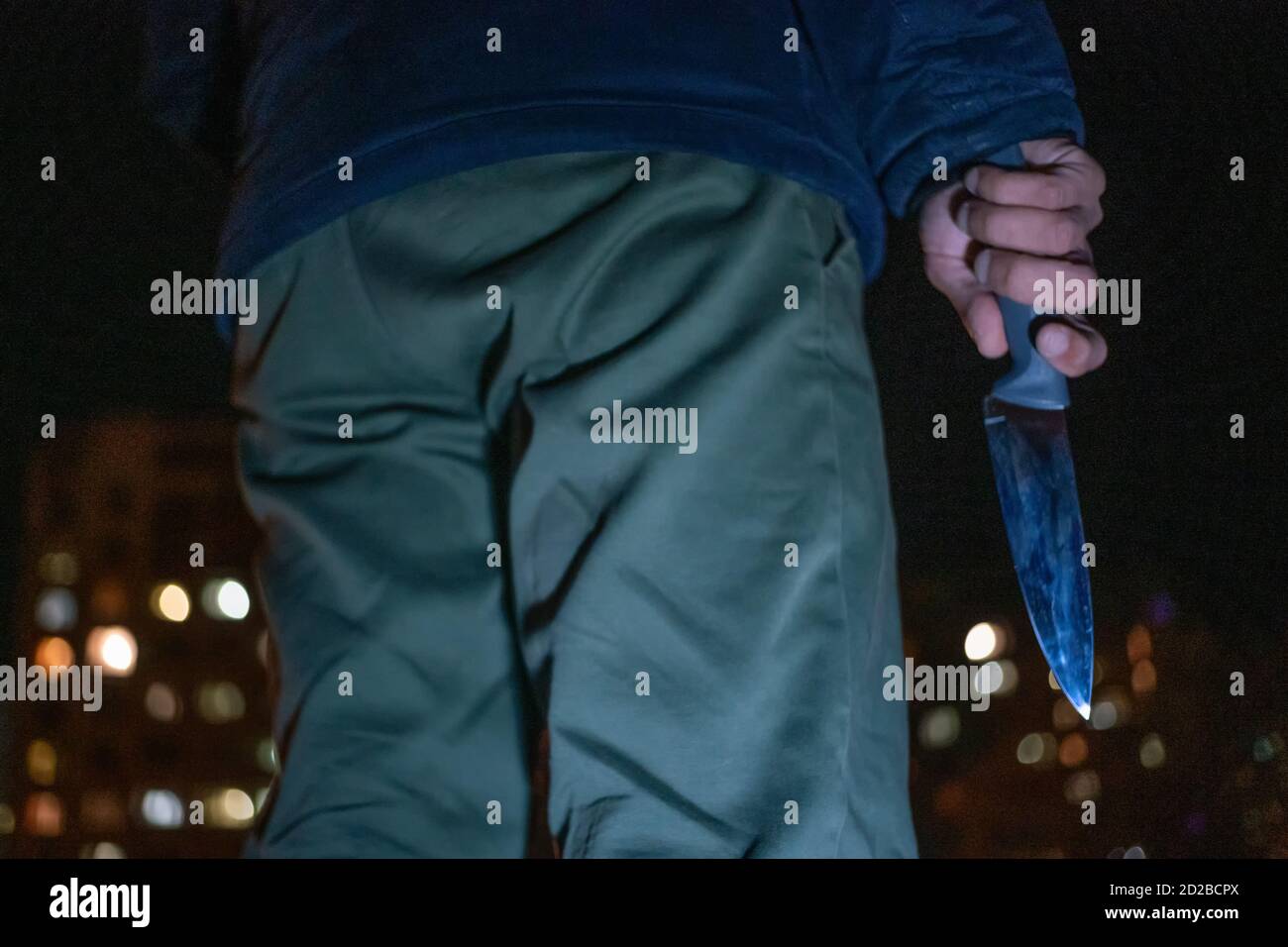 man with a knife in his hands at night on the street close-up. Concept of crimes, robbery Stock Photo