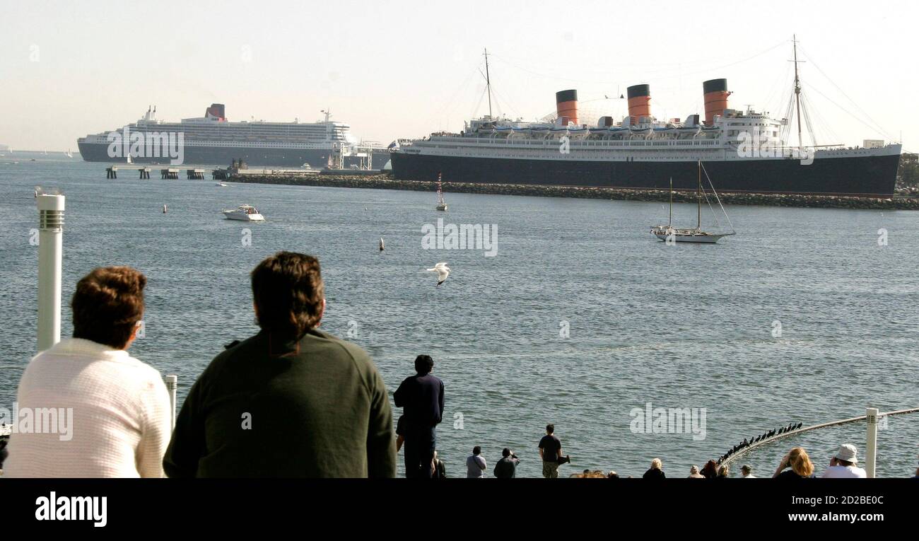 Tourists watch as the Queen Mary 2 (L) , the largest luxury ocean liner in  the world, makes a visit to her predecessor The Queen Mary in Long Beach,  California, February 23,