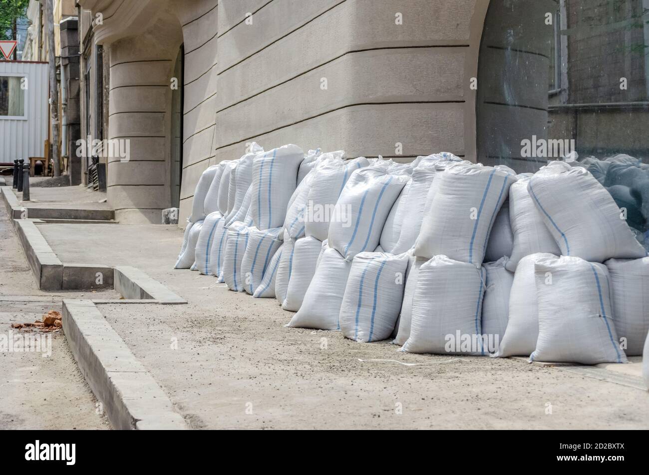 Lots of bags of cement or sand near the wall for building or laying tiles close up Stock Photo