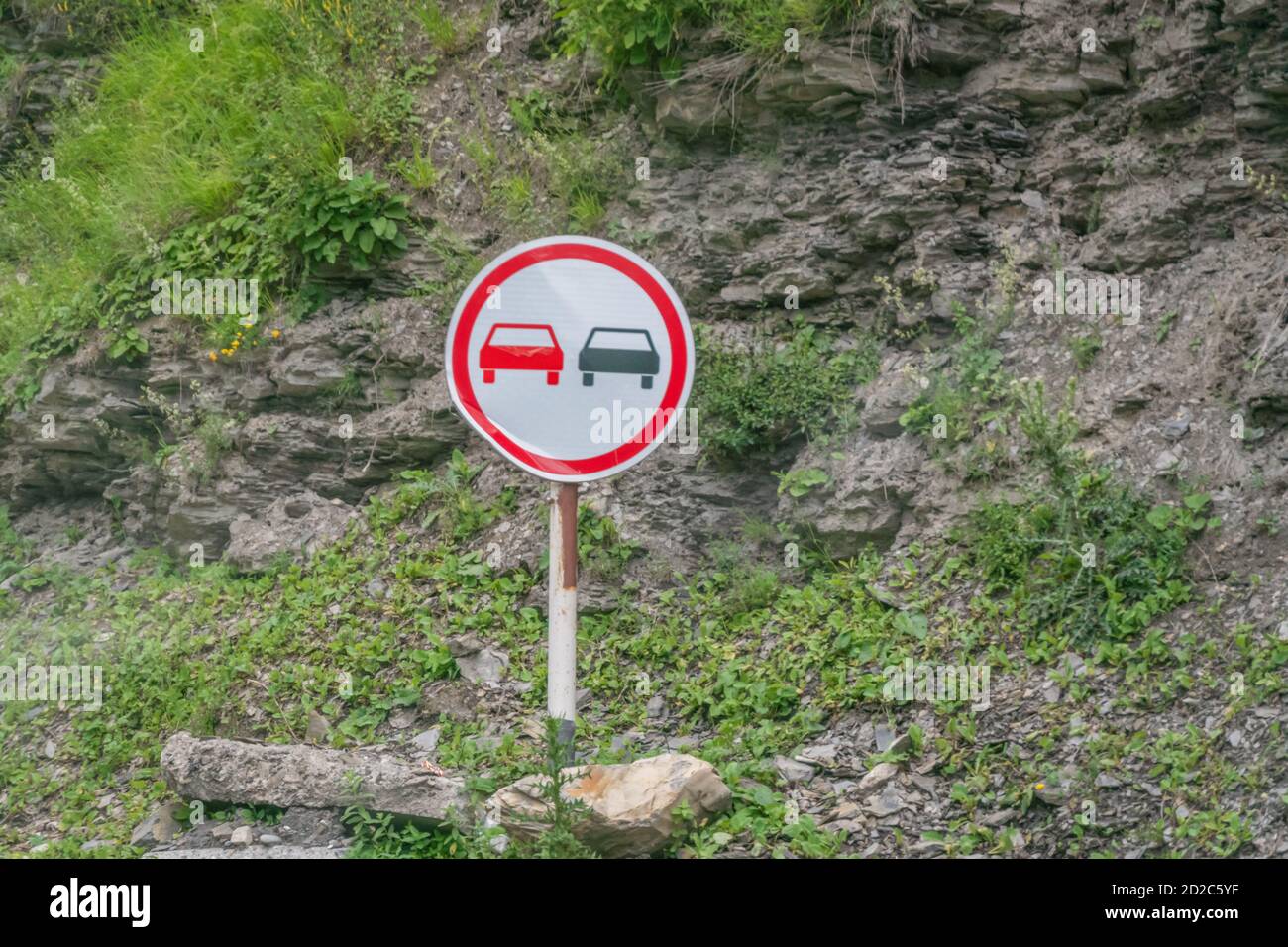 Road sign Overtaking is prohibited costs near the mountain on the road serpentine Stock Photo