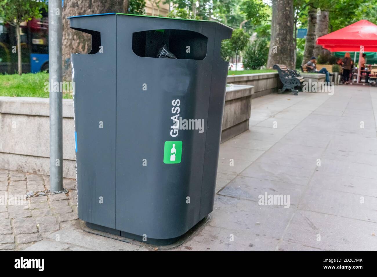 Glass Container Foreground. Black plastic trash bins for separate collection and sorting of paper and glass trash to protect the environment. Stock Photo