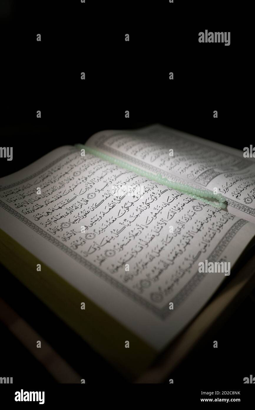 al-Quran is a holy book of Islamic guidance isolated. religion concept. An open page of Quran on wooden stand above the prayer mat open page of Quran Stock Photo