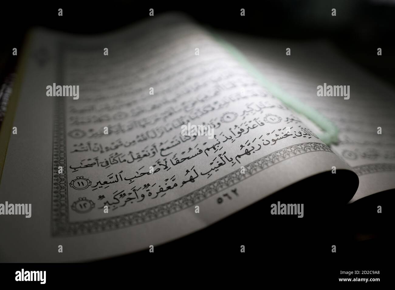al-Quran is a holy book of Islamic guidance isolated. religion concept. An open page of Quran on wooden stand above the prayer mat open page of Quran Stock Photo