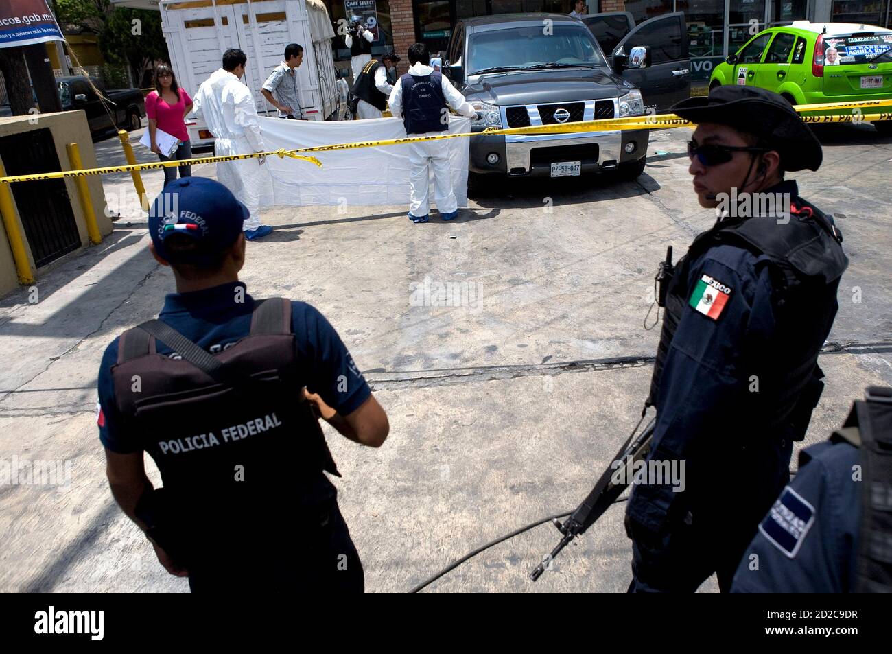 Federal police guard the crime scene as forensic experts prepare to remove  the body of lawyer Rogelio Garza Cantu after he was killed by unknown  assailants outside a store in Monterrey, northern
