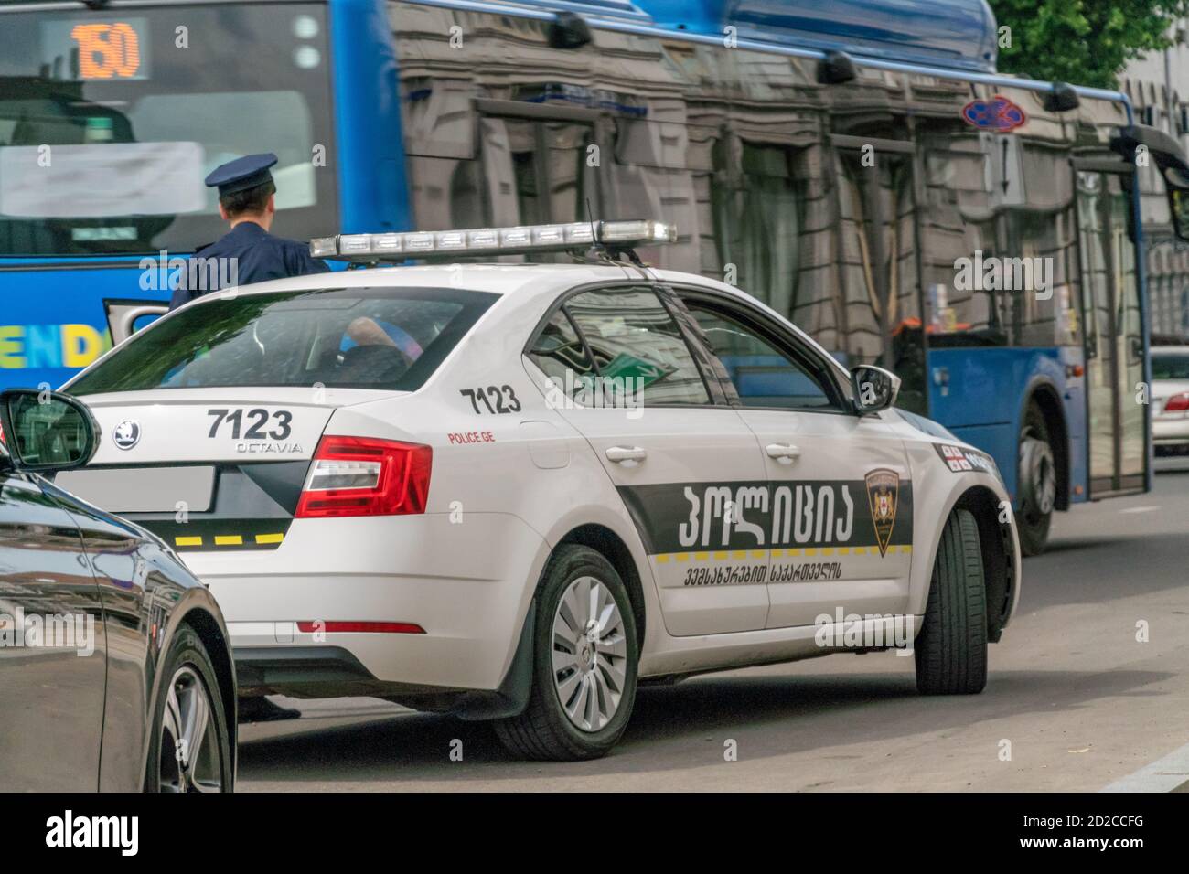 Tbilisi, Georgia - June 28 2019: Police car on the asphalt road in the city on a sunny clear day, policeman near the car Stock Photo