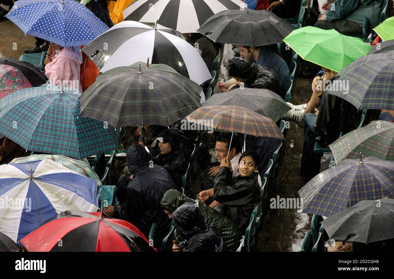Cricket fans huddle under umbrellas as rain delays the start of play in the first one-day international between South Africa and India in Johannesburg November 19, 2006. REUTERS/Mike Hutchings (SOUTH AFRICA) Stock Photo