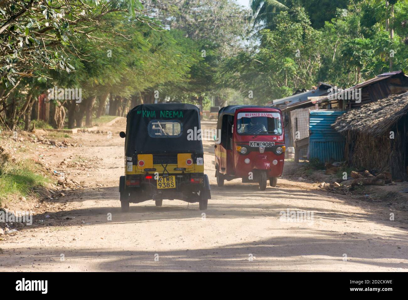 Tuk-tuks or auto rickshaws driving along a dusty beach road, Diani, Kenya Stock Photo