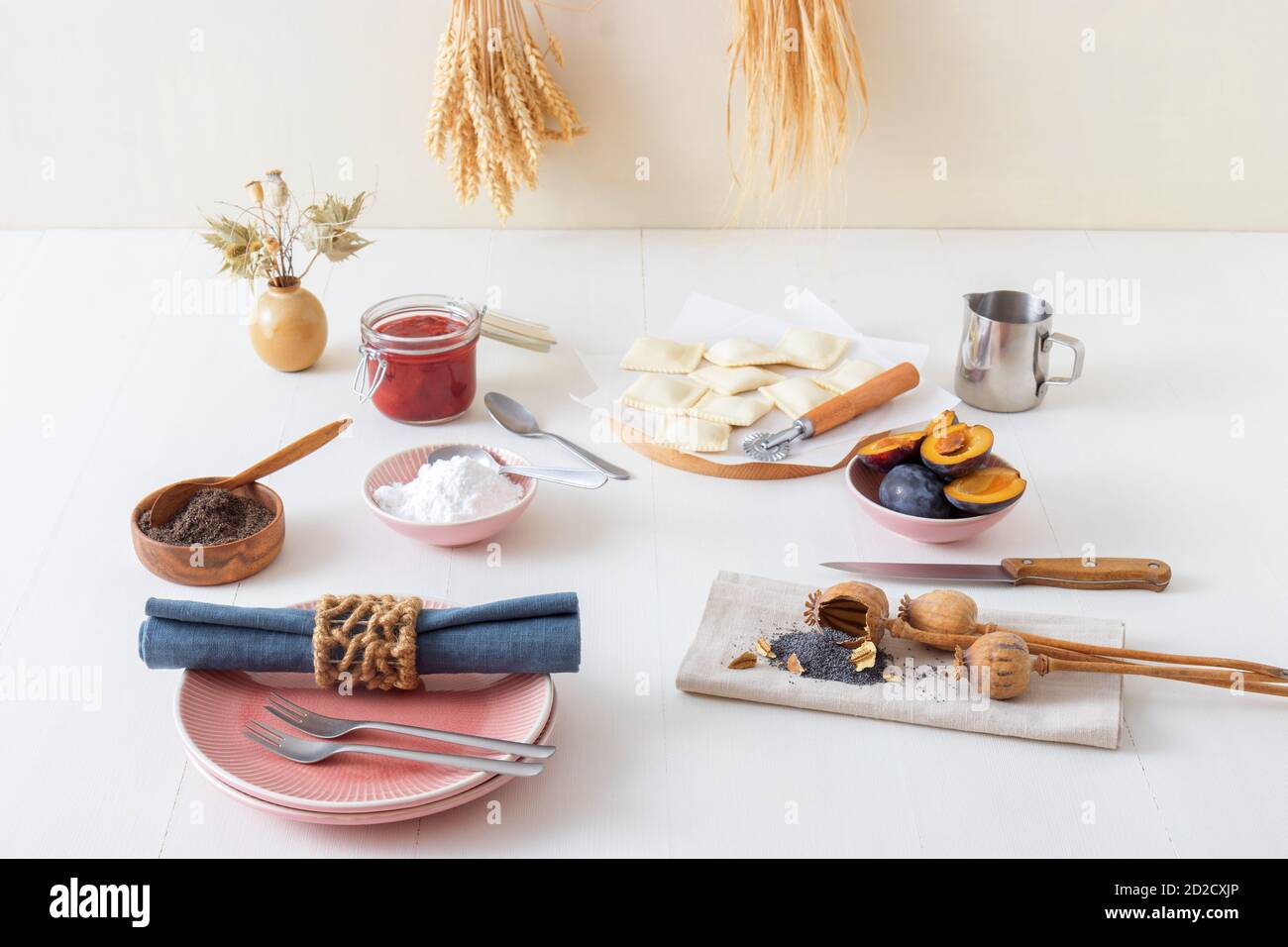 Pastry parcels filled with plum marmalade, dusted with poppy seed and icing sugar. Tasty poppy seed dessert or main course. White wooden table backgro Stock Photo