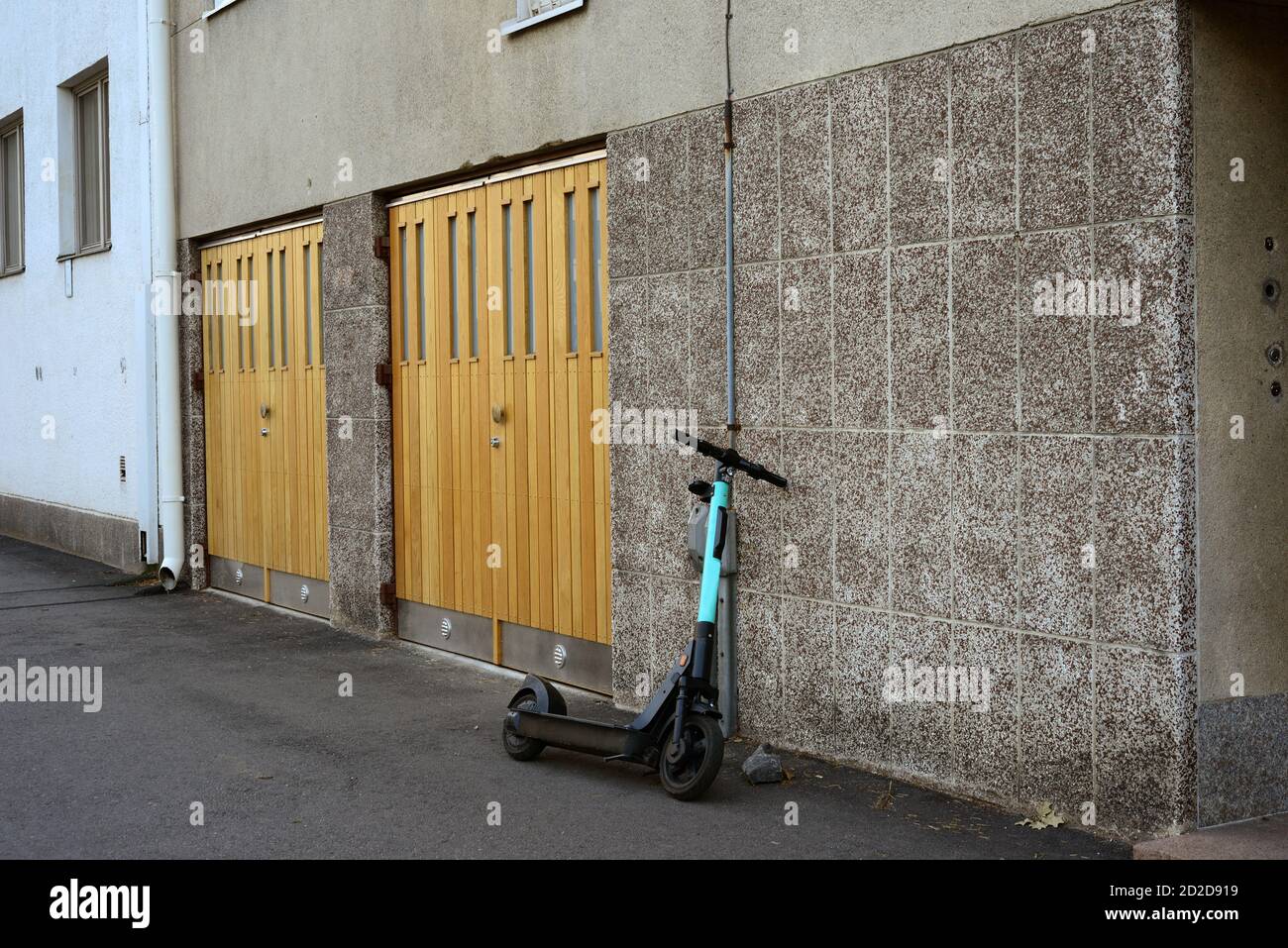 an electric scooter is parked near the garage door of an apartment building Stock Photo