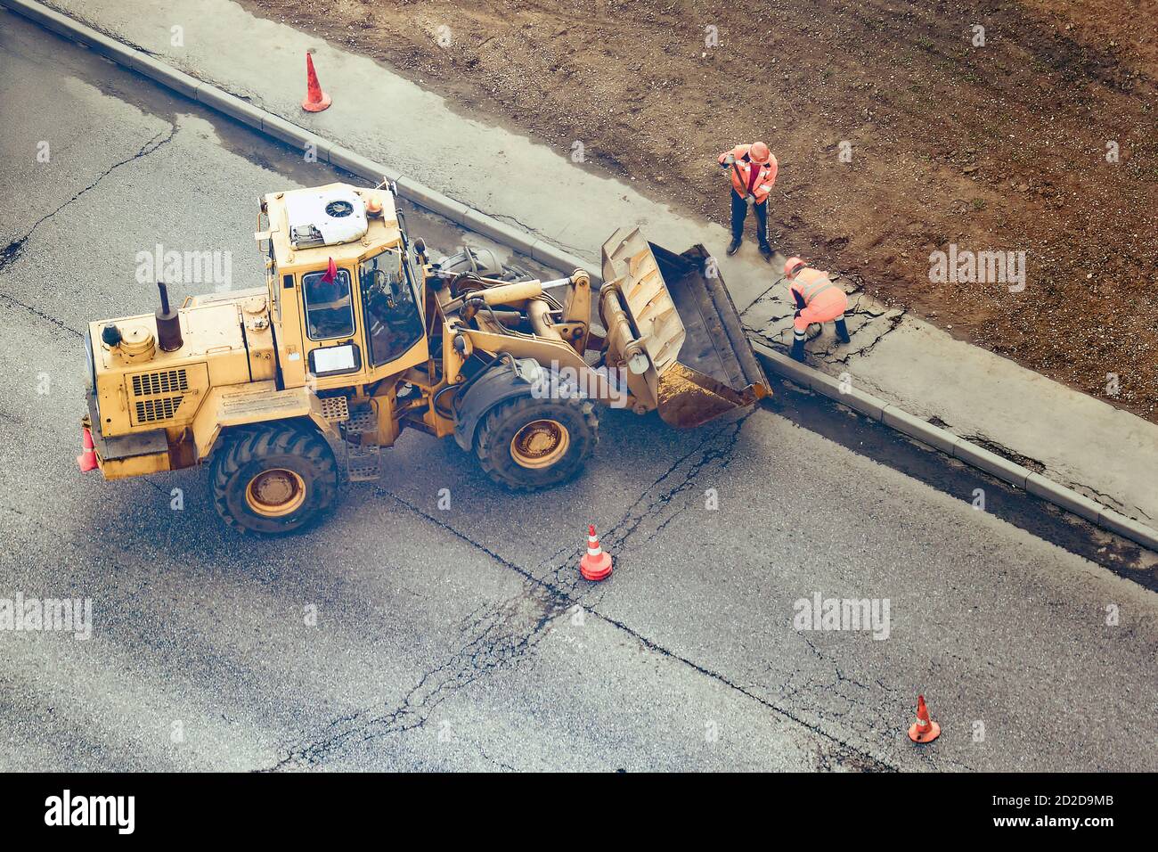 Workers remove the asphalt by putting it in the bucket of the excavator