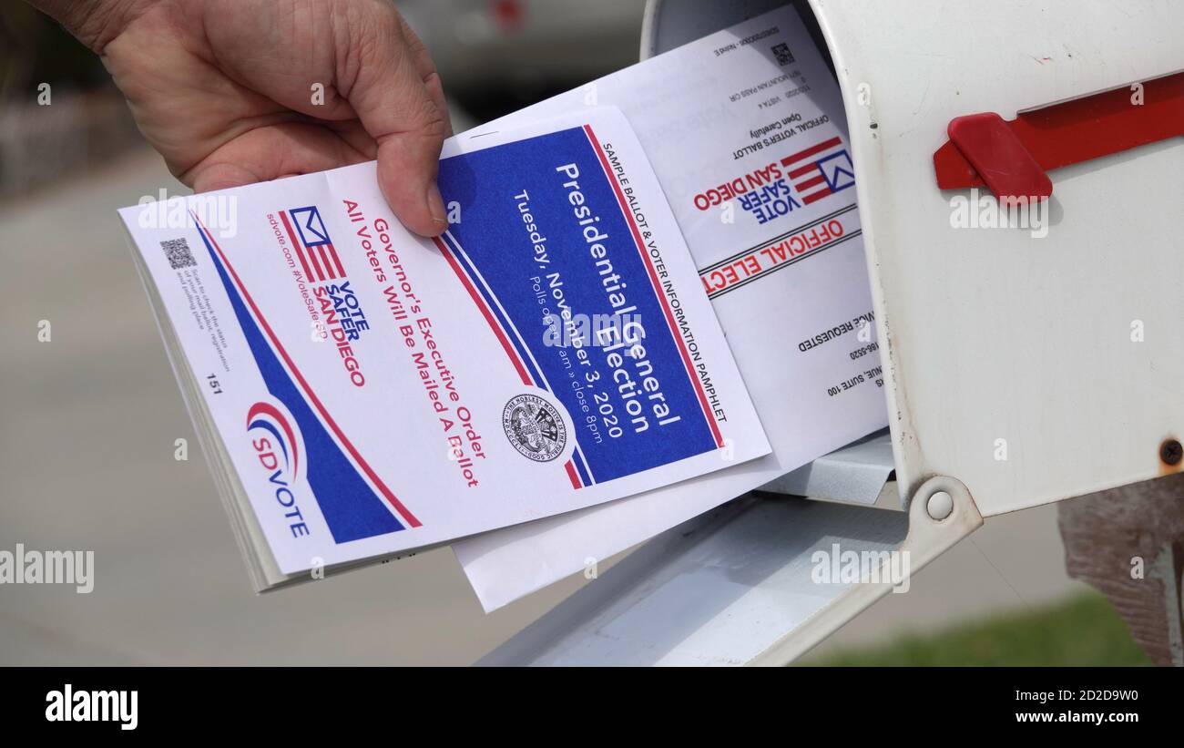 Close up of a man's hand pulling mail ballot and voter booklet from post box. Illustrative editorial taken in Vista, CA / USA on October 6, 2020. Stock Photo