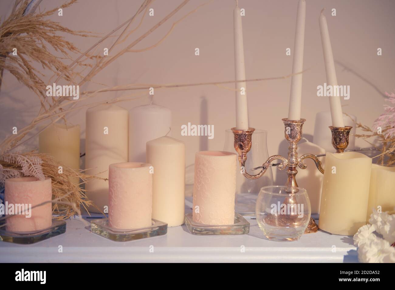 Vintage candles in a candlestick and flowers on the shelf, closeup