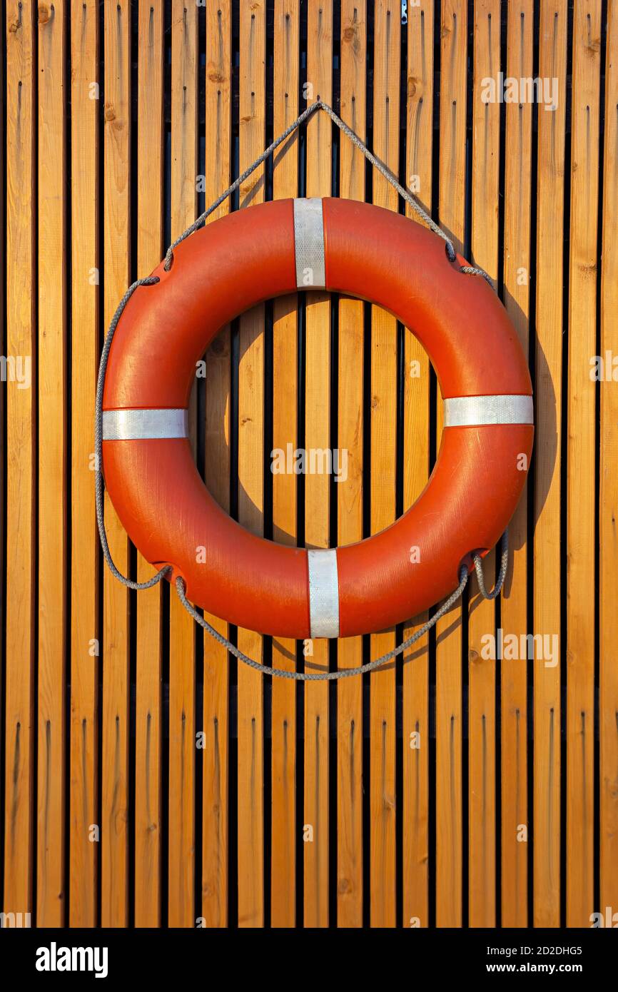 Lifebuoy hanging on a wooden plank wall at sunset Stock Photo