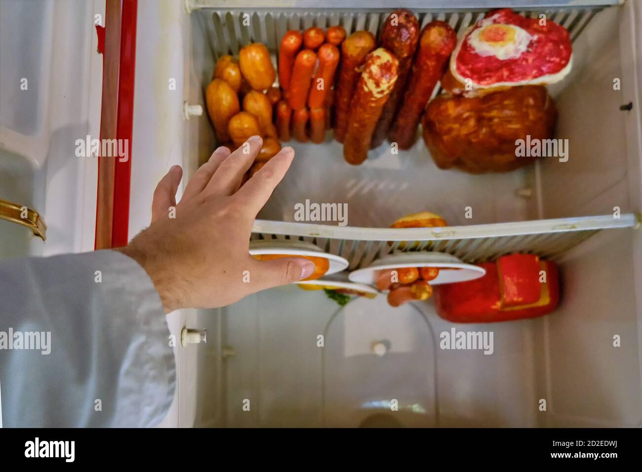 A man's hand reaches for the food in the fridge upside down Stock Photo