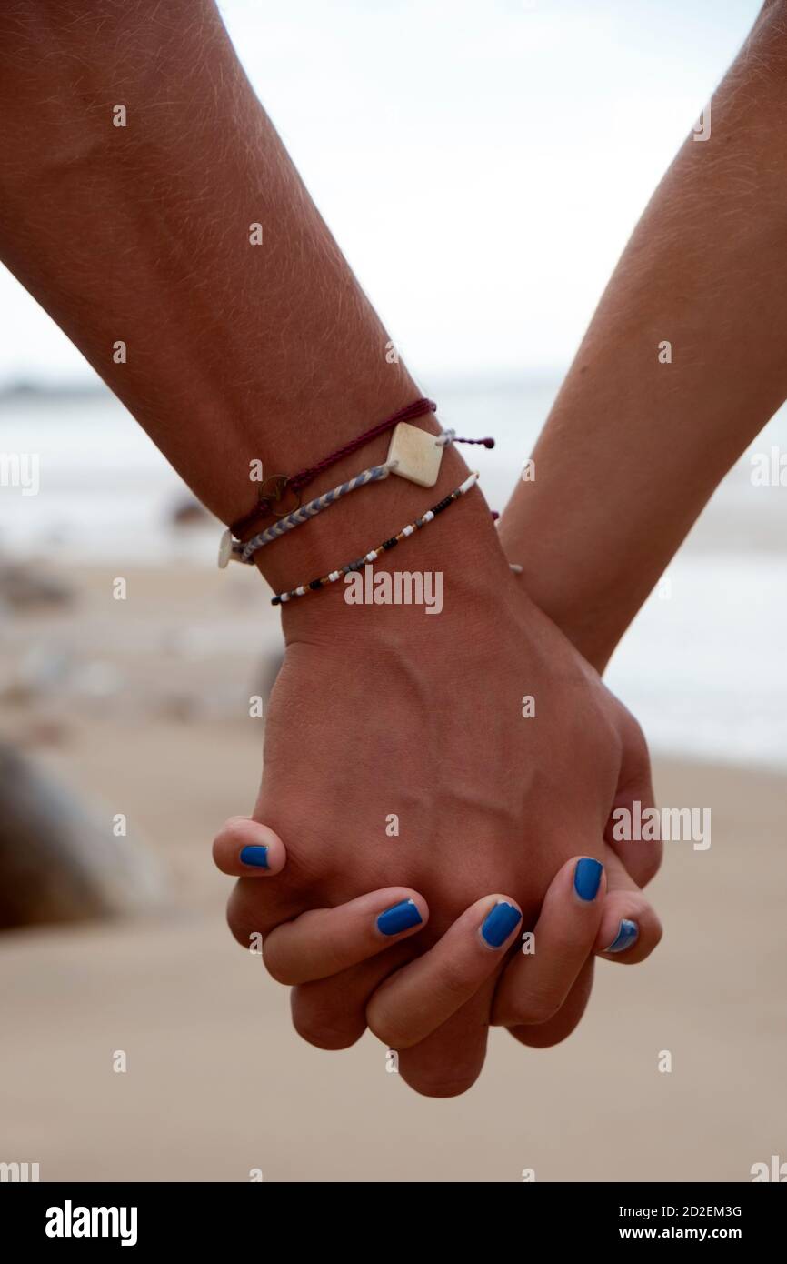 Young couple holding hands on the beach Stock Photo - Alamy