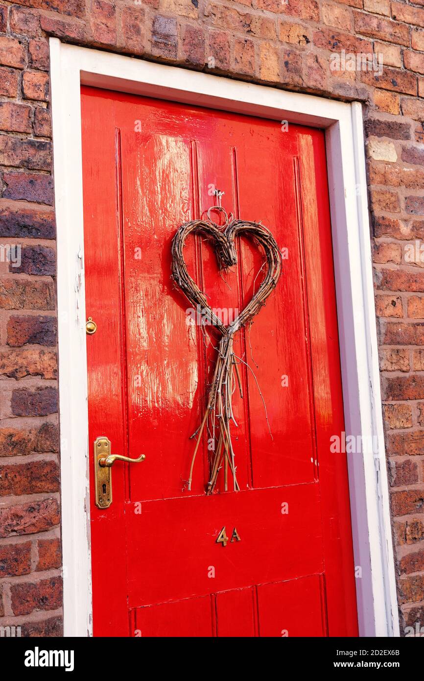 Beautiful red front door with wicker heart wreath Stock Photo