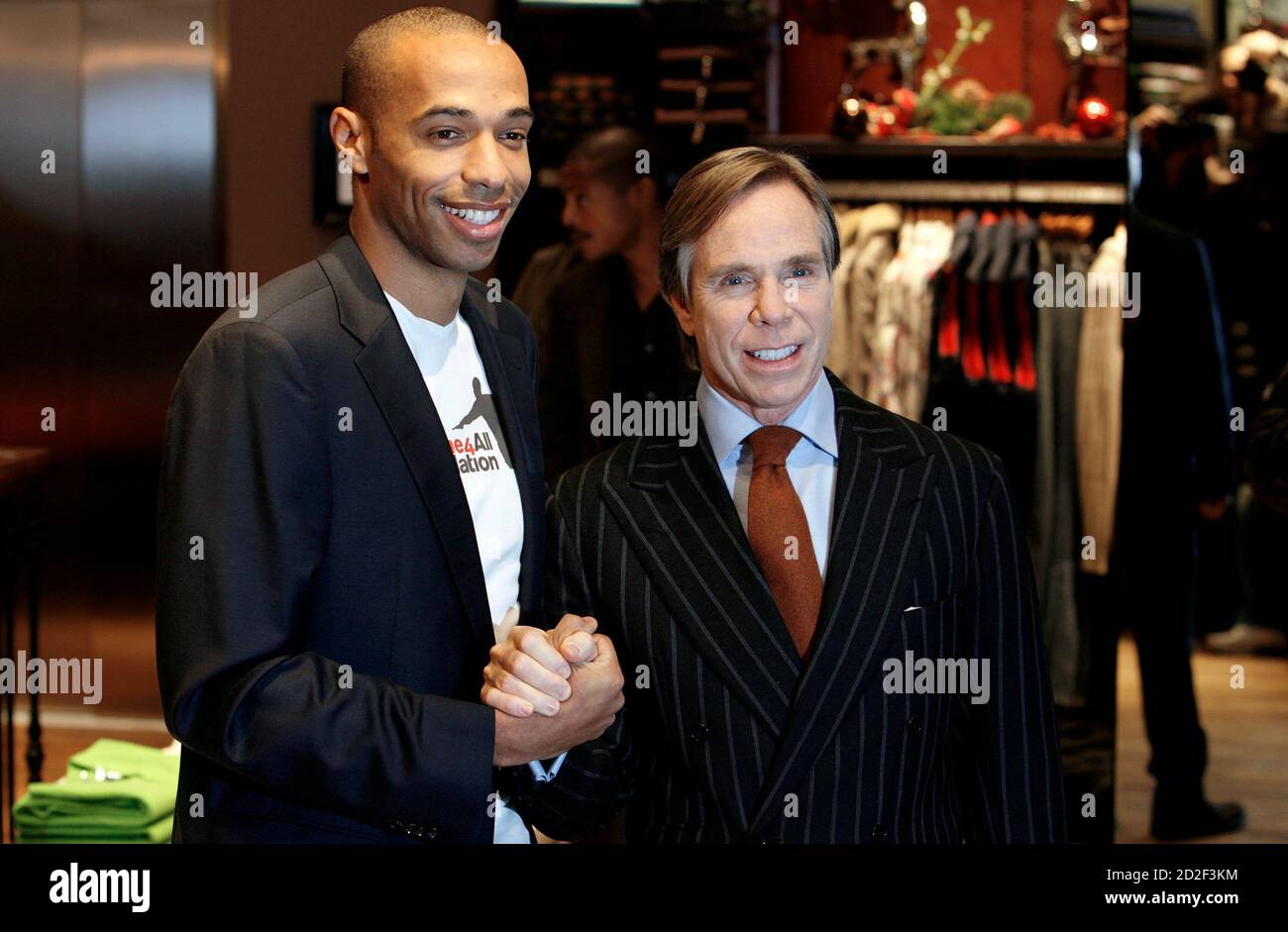 Fashion designer Tommy Hilfiger (R) and Arsenal soccer player Thierry Henry  pose for photographers during the opening of Hilfiger's new store in  central London December 5, 2006. REUTERS/Alessia Pierdomenico (BRITAIN  Stock Photo -