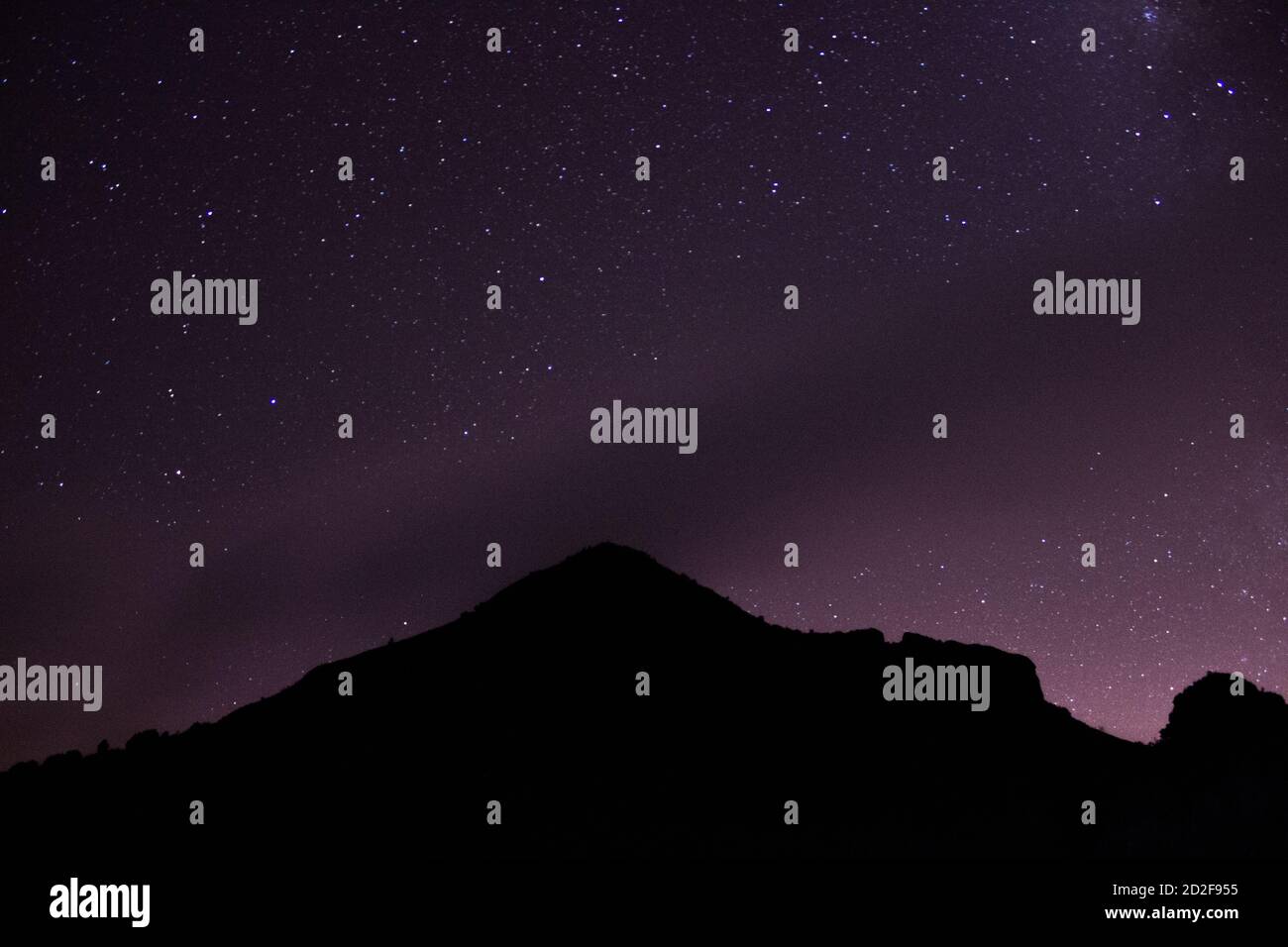 Mountain with a purple star sky and city lights Stock Photo - Alamy