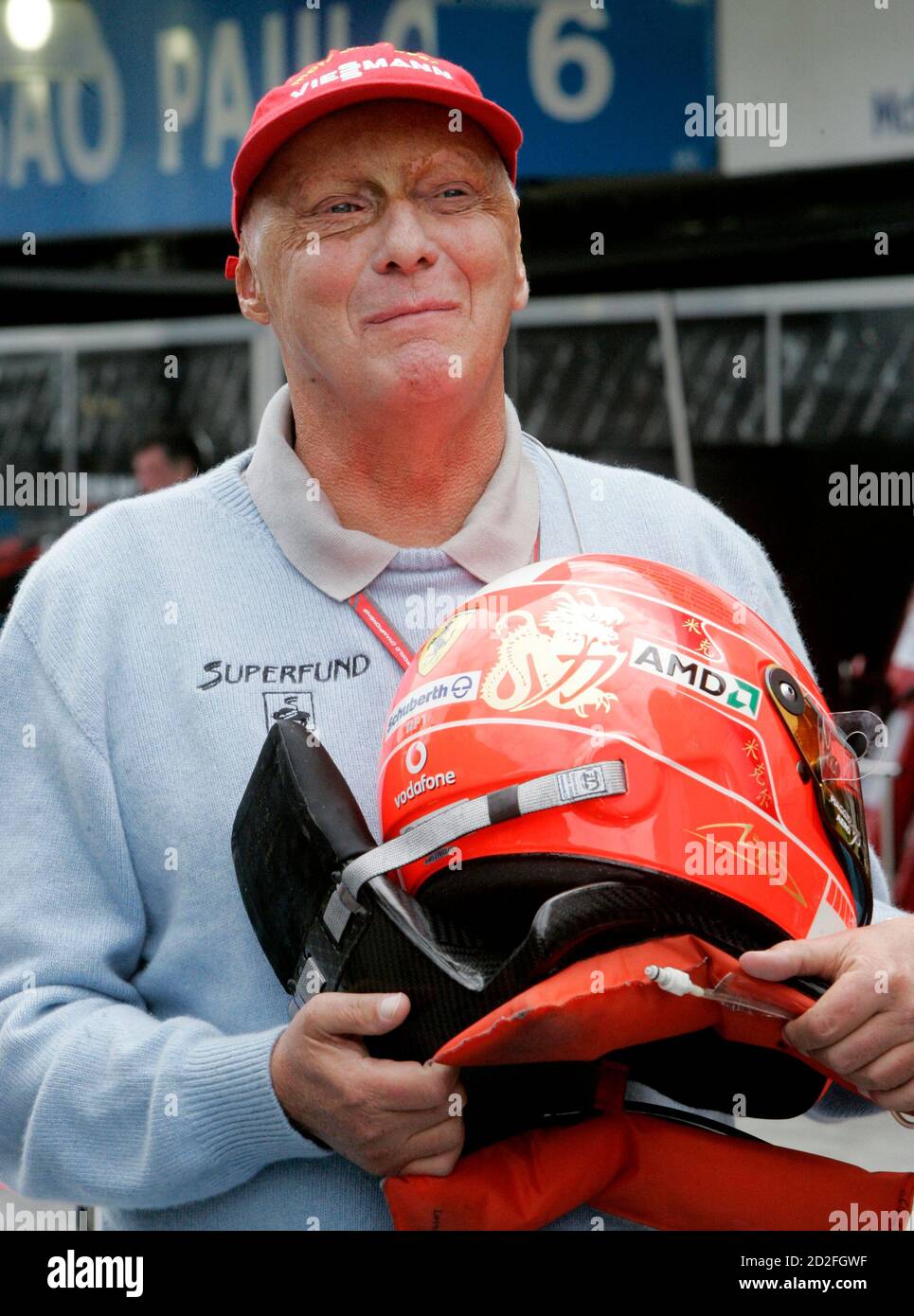 Niki Lauda, former Formula One world champion for the Ferrari team, holds  the helmet of Ferrari's current driver Michael Schumacher of Germany as  drivers prepared for the time trial at the Interlagos