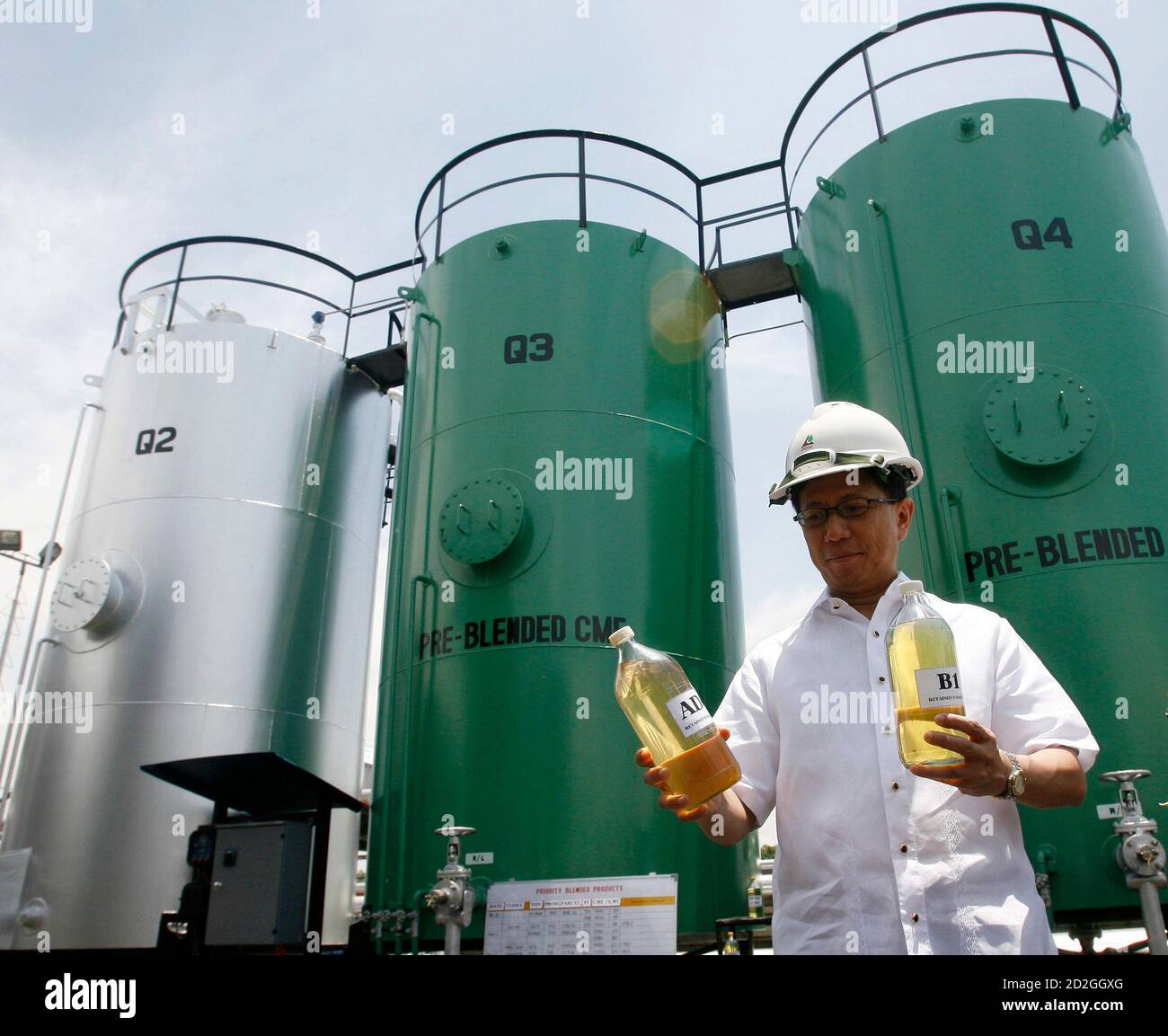 Energy Secretary Raphael Lotilla holds biodiesel samples in front of  pre-blending tanks during an inspection of an oil depot facility in Manila  May 7, 2007. The Philippines' biofuels law came into effect