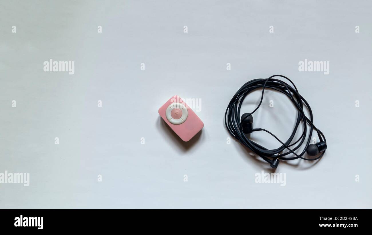 Pink and white coloured mp3 player with a black earphone on white ...