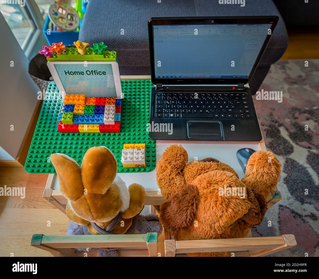 View from the top at a cute homeoffice scene with a stuffed teddy bear and his friend a rabbit working at a laptop. Stock Photo