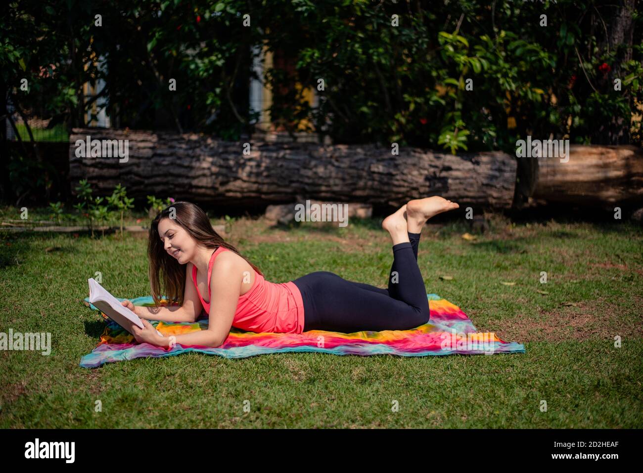 Woman reading a book while lying in the front yard Stock Photo