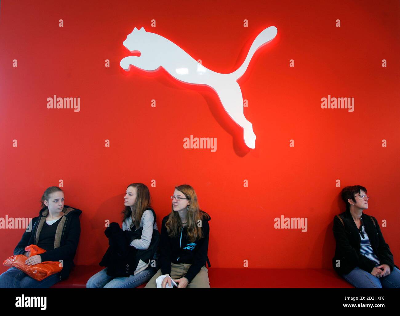 People sit under a Puma sign at the factory outlet store in Herzogenaurach  near Nuremberg April 10, 2007. French retailer PPR on Tuesday made a 5.3  billion euro ($7.07 billion) bid to