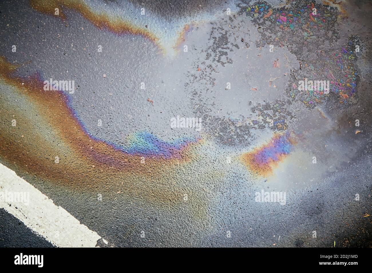 Colorful gas stain on wet asphalt. Oil stain caused by a leak under a
