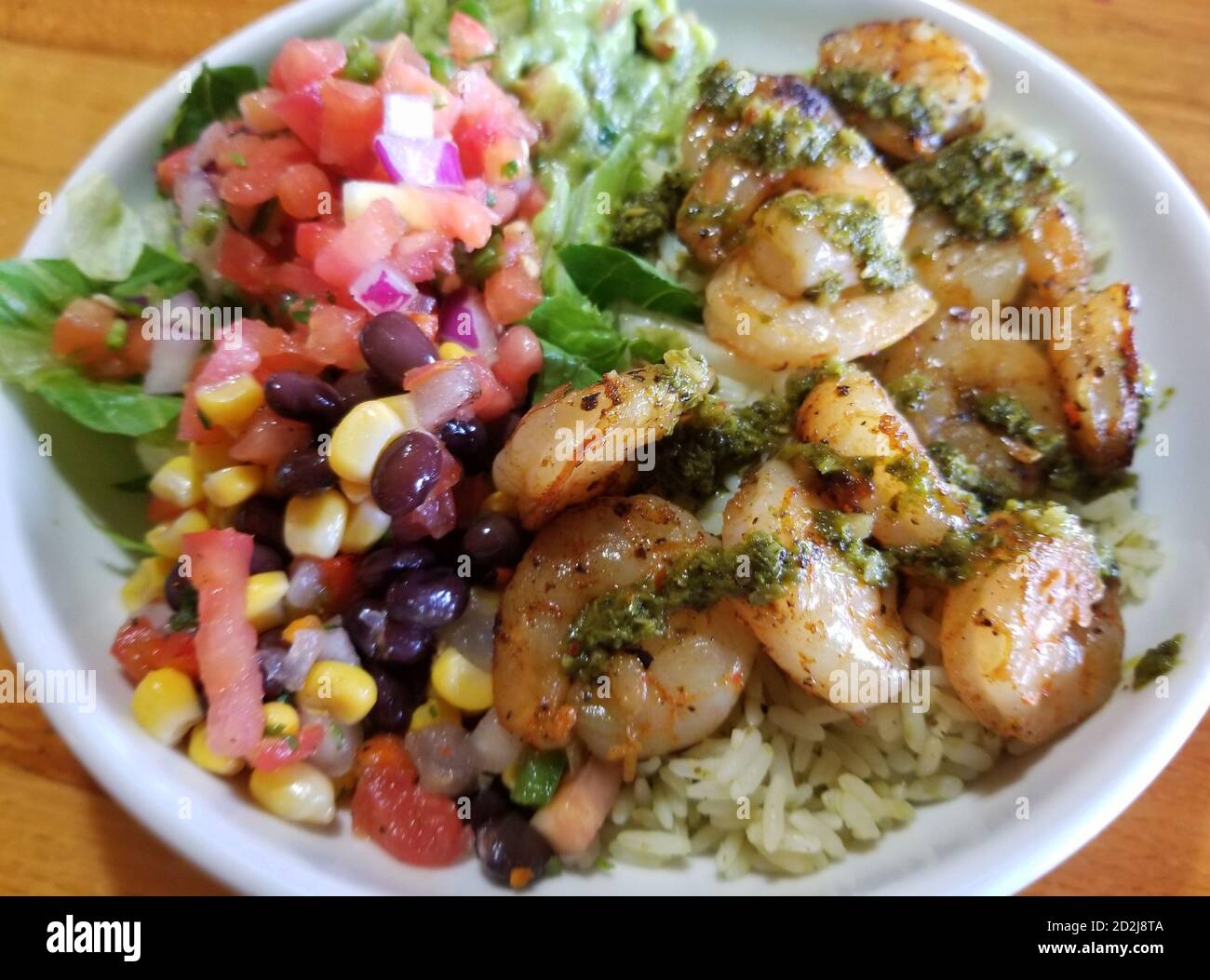 TexMex shrimp salad inside a bowl with guacamole, salsa and tortilla