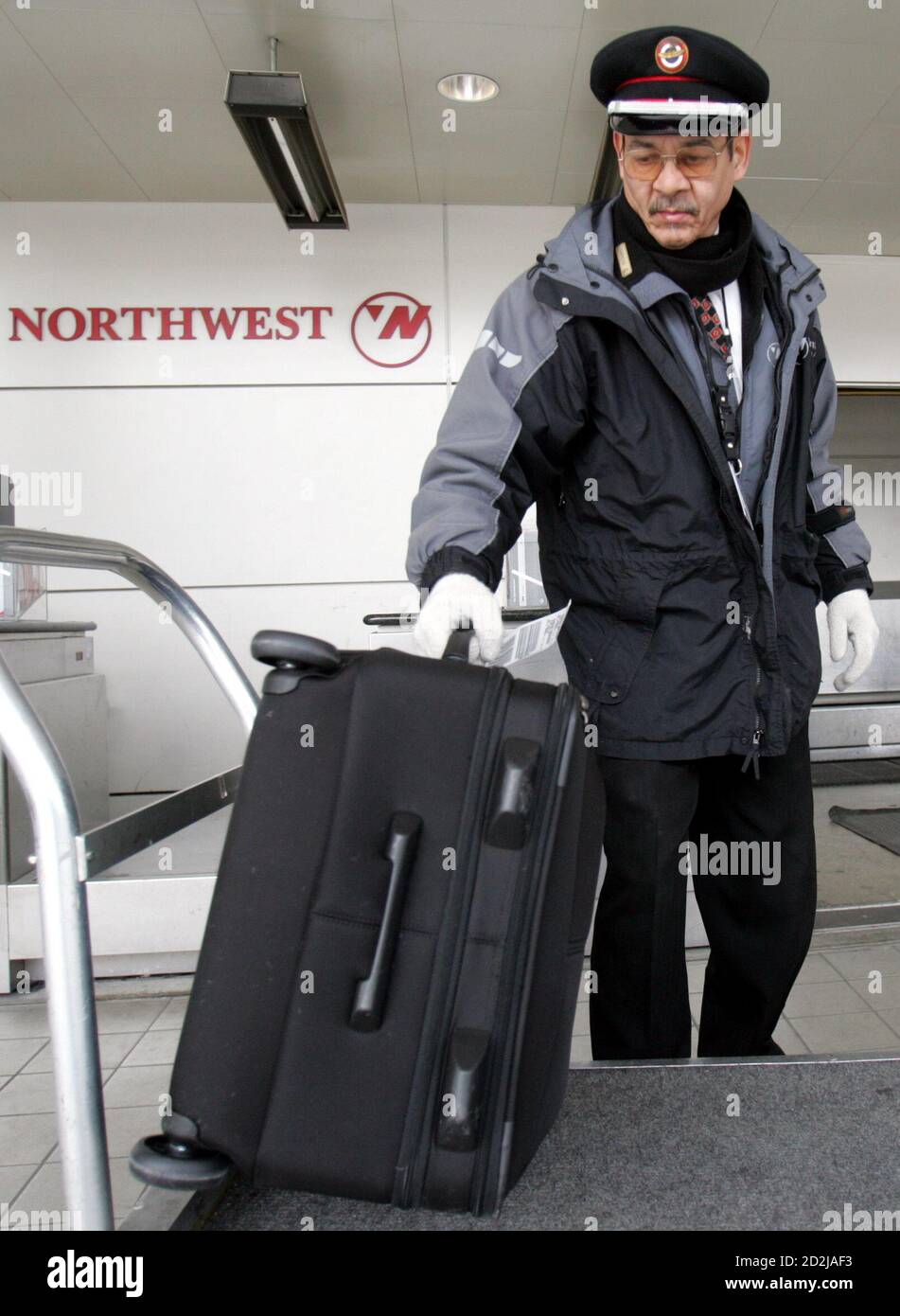 A Northwest Airlines skycap, Richard Reid, checks in luggage at the departure terminal of Detroit Metropolitan Airport in Romulus, Michigan March 1, 2006. Bankrupt Northwest Airlines on Wednesday reached a tentative labor deal with its flight attendants union but still faces a possible strike should it fail to reach agreement with its pilots ahead of a court-imposed deadline. Reid has worked for Northwest for 33 years. REUTERS/Rebecca Cook Stock Photo