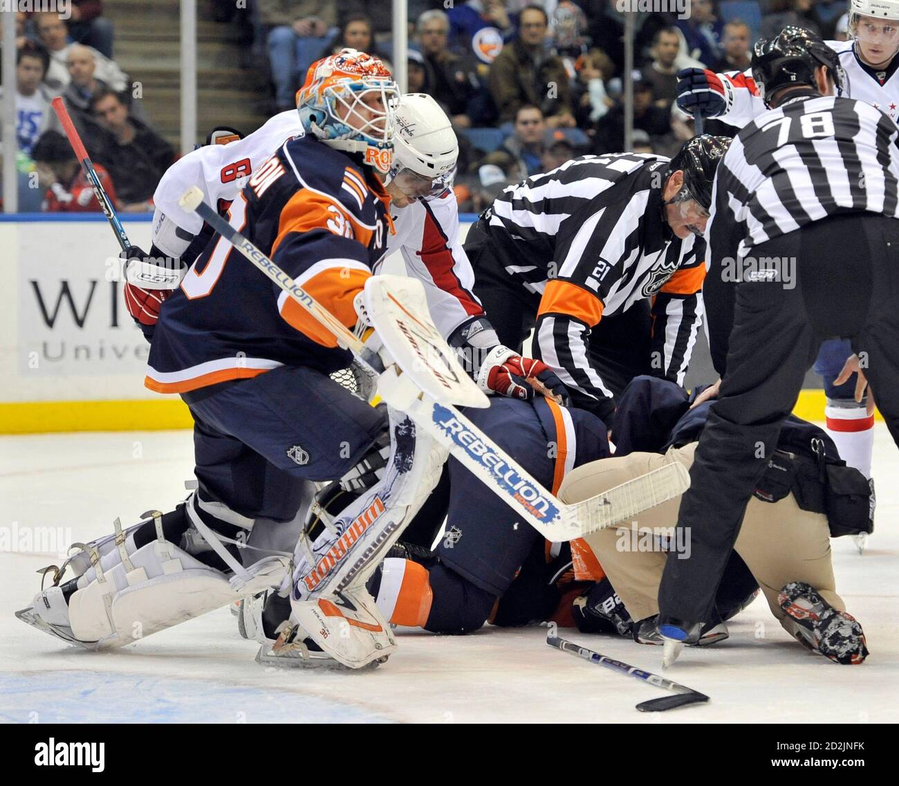 New York Islanders goalie Dwayne Roloson and Washington Capitals captain  Alex Ovechkin (8) bend over Islanders defenseman Jack Hillen (on ice) after  he was hurt during the first period of their NHL