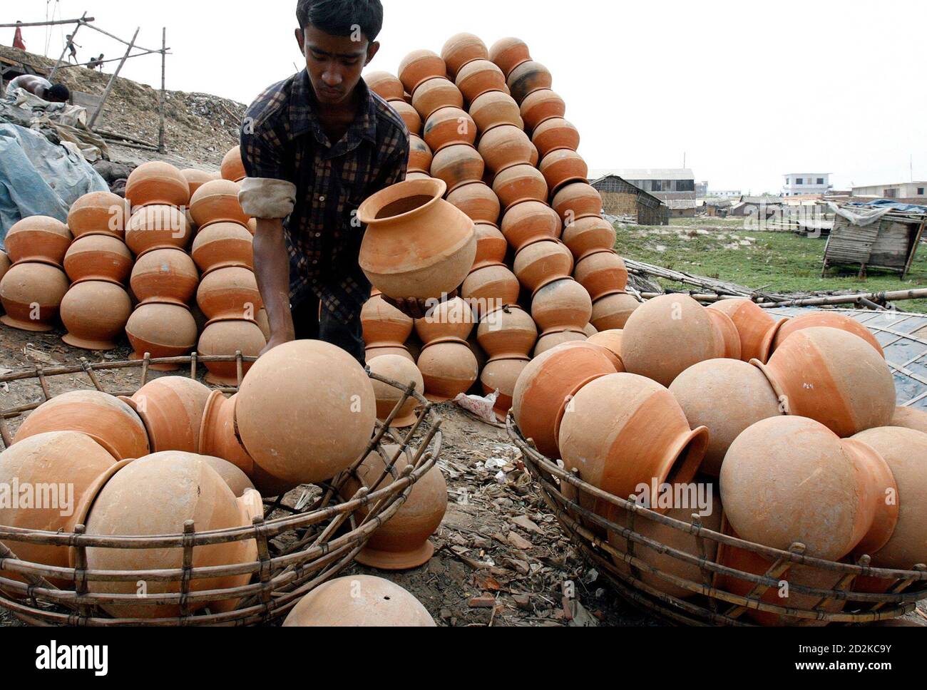 A Bangladeshi vendor loads clay pots on a basket on the banks of river