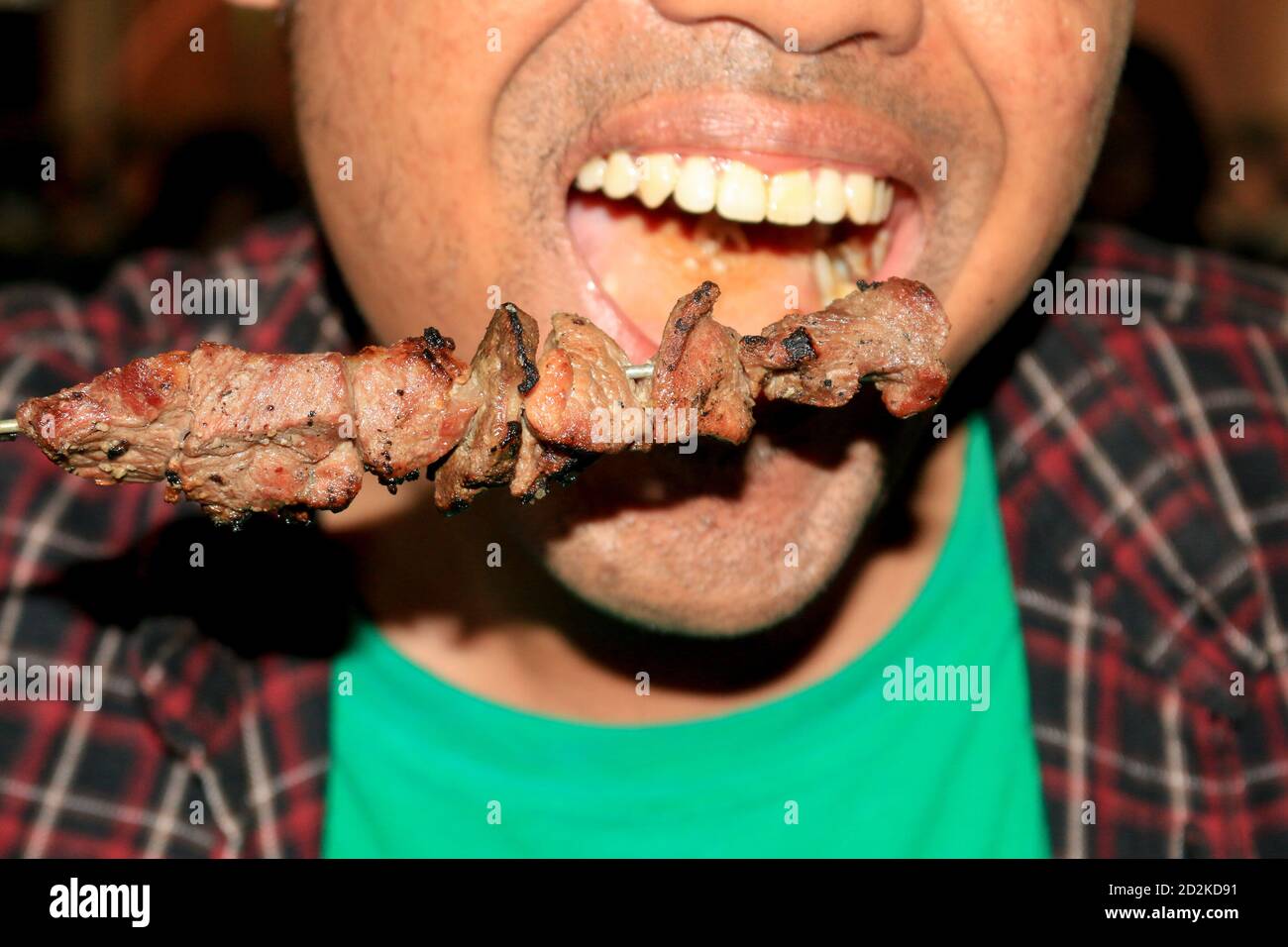 A man eating Sate Klathak or Klatak Satay is a unique goat satay or mutton satay dish with steel stick, traditional satay from Yogyakarta, Indonesia. Stock Photo