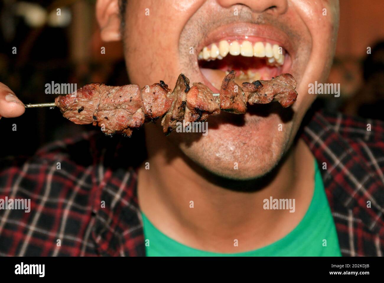 A man eating Sate Klathak or Klatak Satay is a unique goat satay or mutton satay dish with steel stick, traditional satay from Yogyakarta, Indonesia. Stock Photo